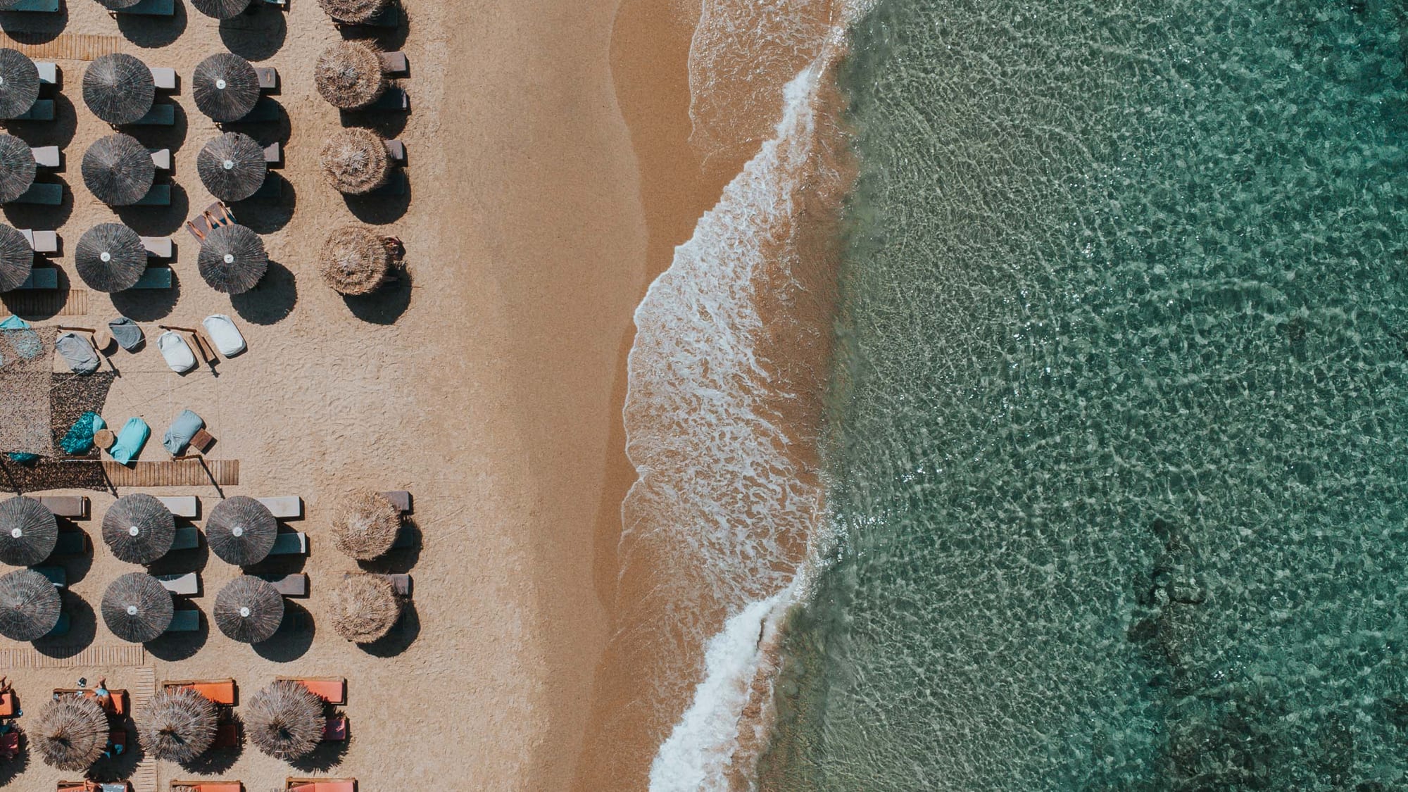 Aerial view of the beach umbrellas along the turquoise surf
