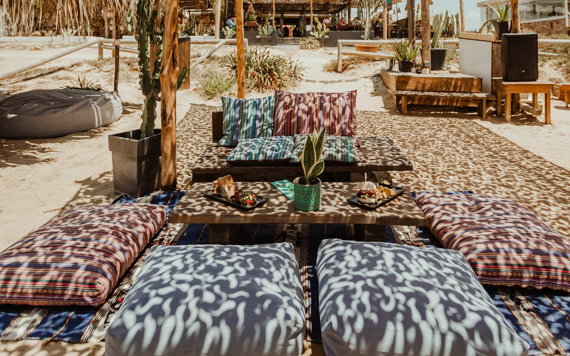 Lounge cushions and low tables on the sand at tohu beach bar