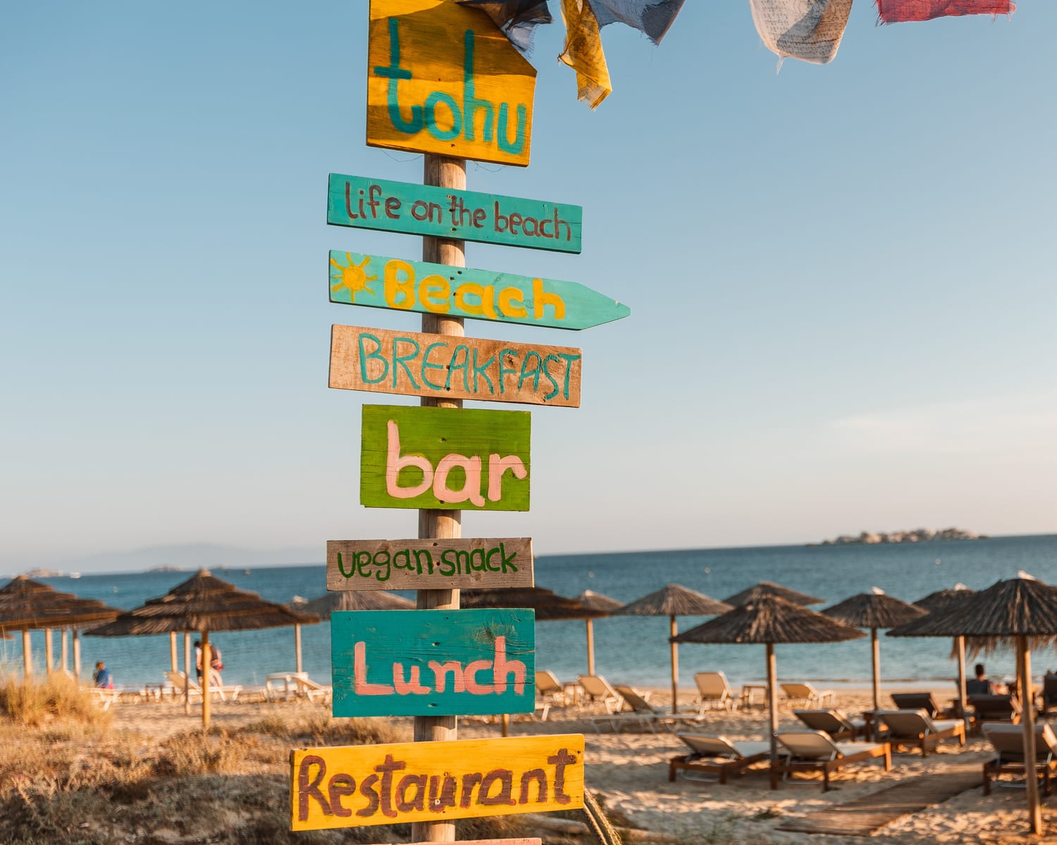 The colourful tohu totem signpost on the beach — breakfast, bar, lunch, restaurant