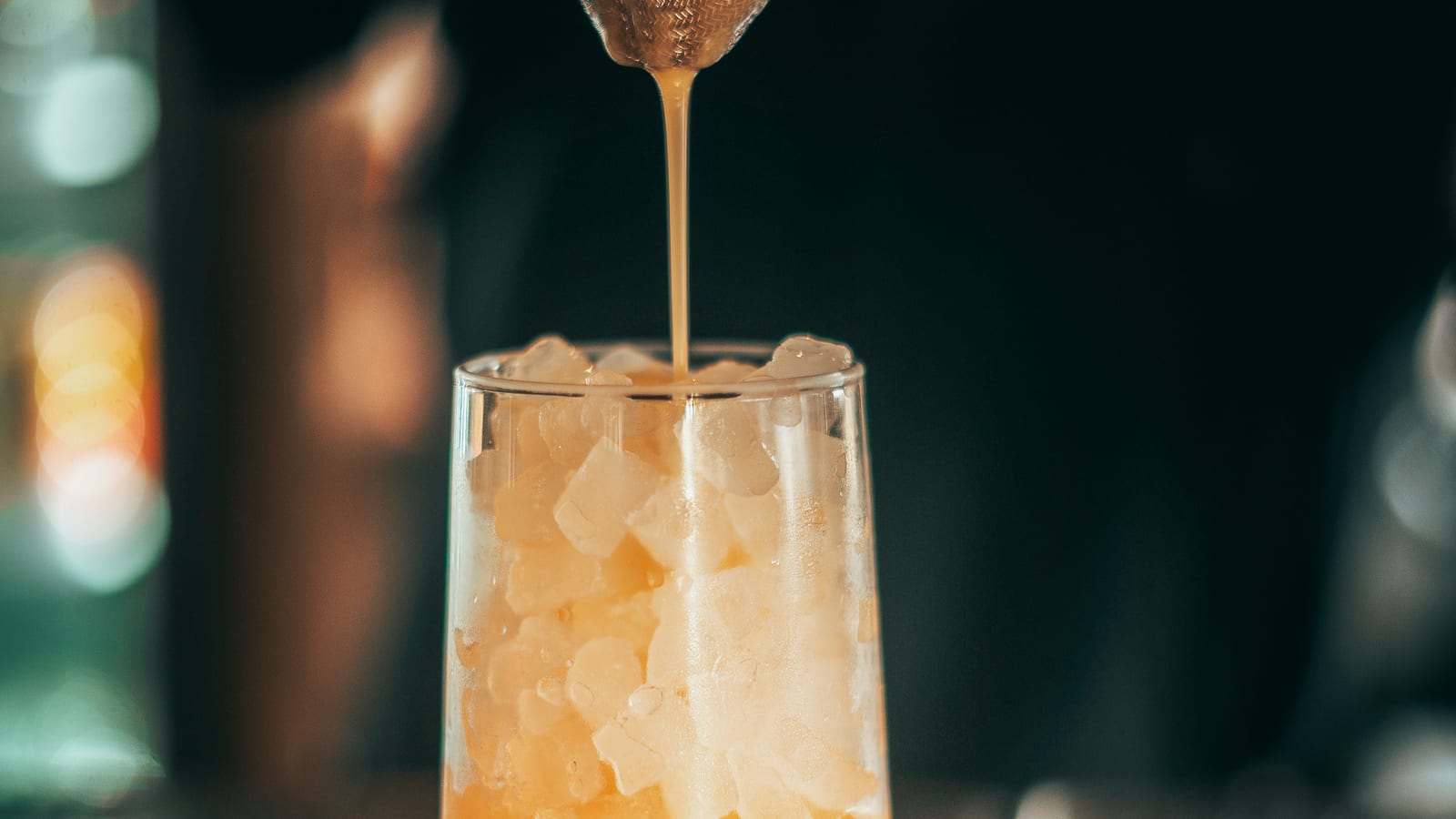 A bartender pouring a drink over crushed ice