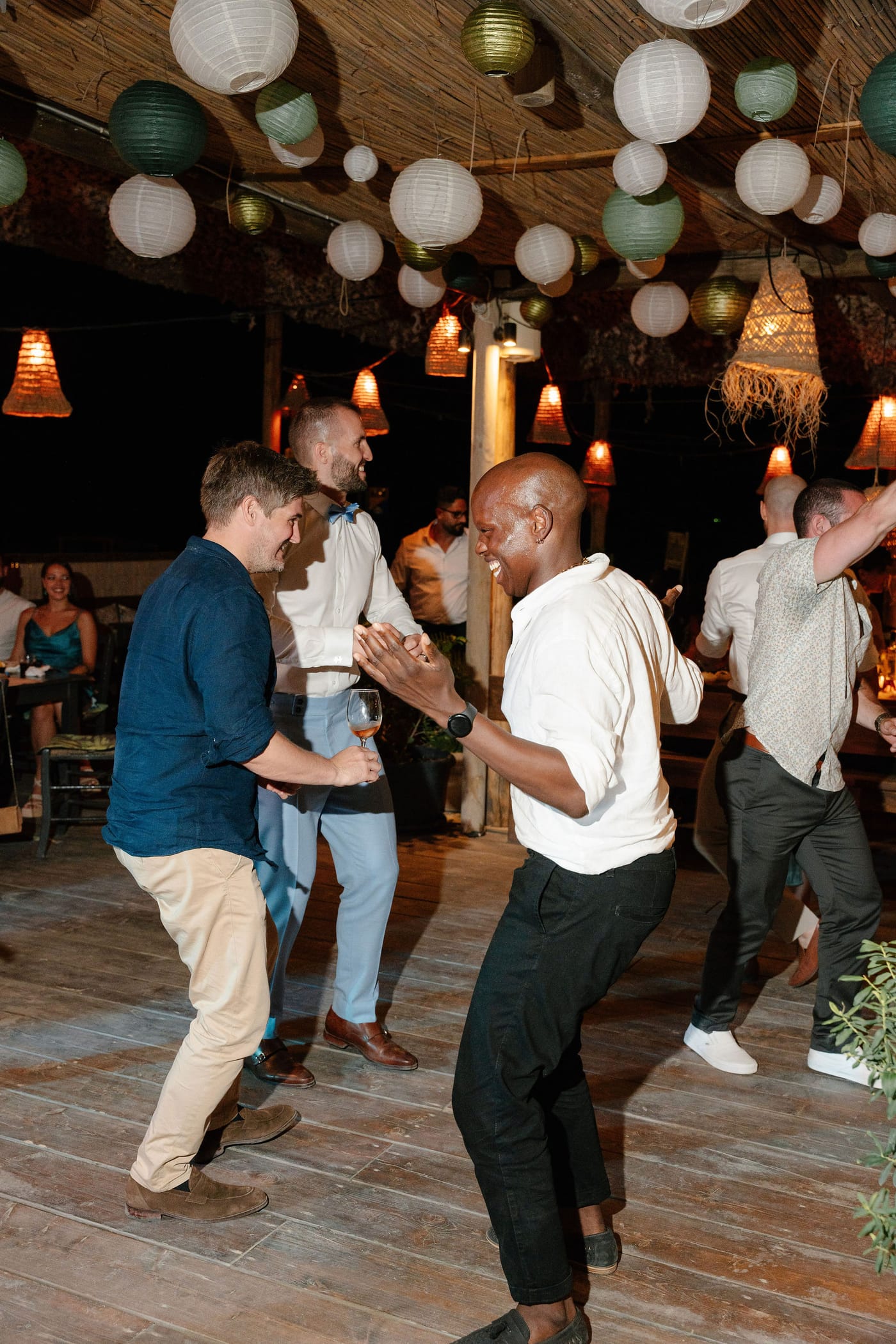 Guests dancing under hanging lanterns at the beach party