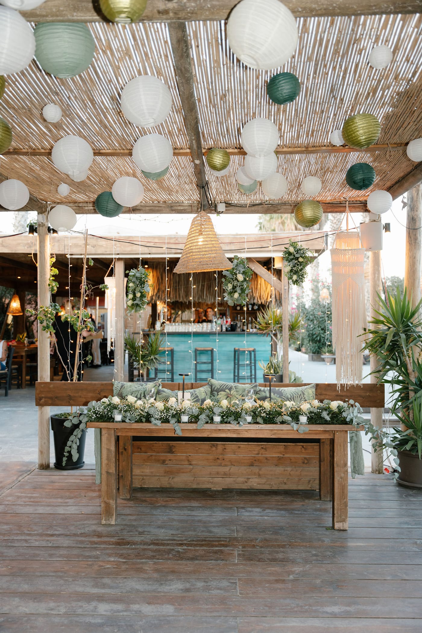 A sweetheart table dressed with flowers under hanging paper lanterns
