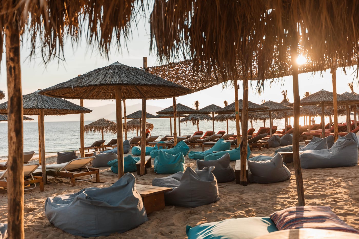 Reed umbrellas and bean bags on the beach at golden hour