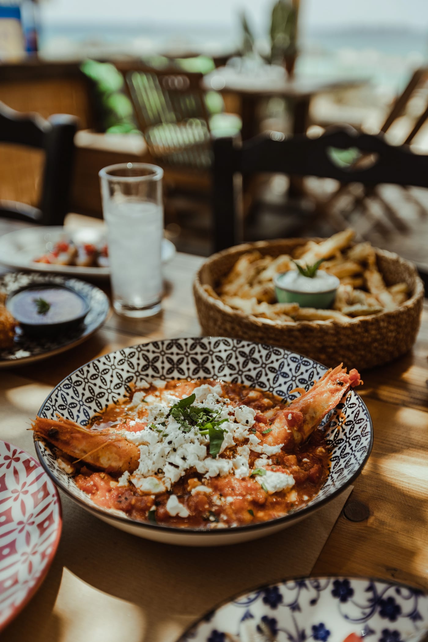 Shrimps saganaki with feta in tomato, the sea behind
