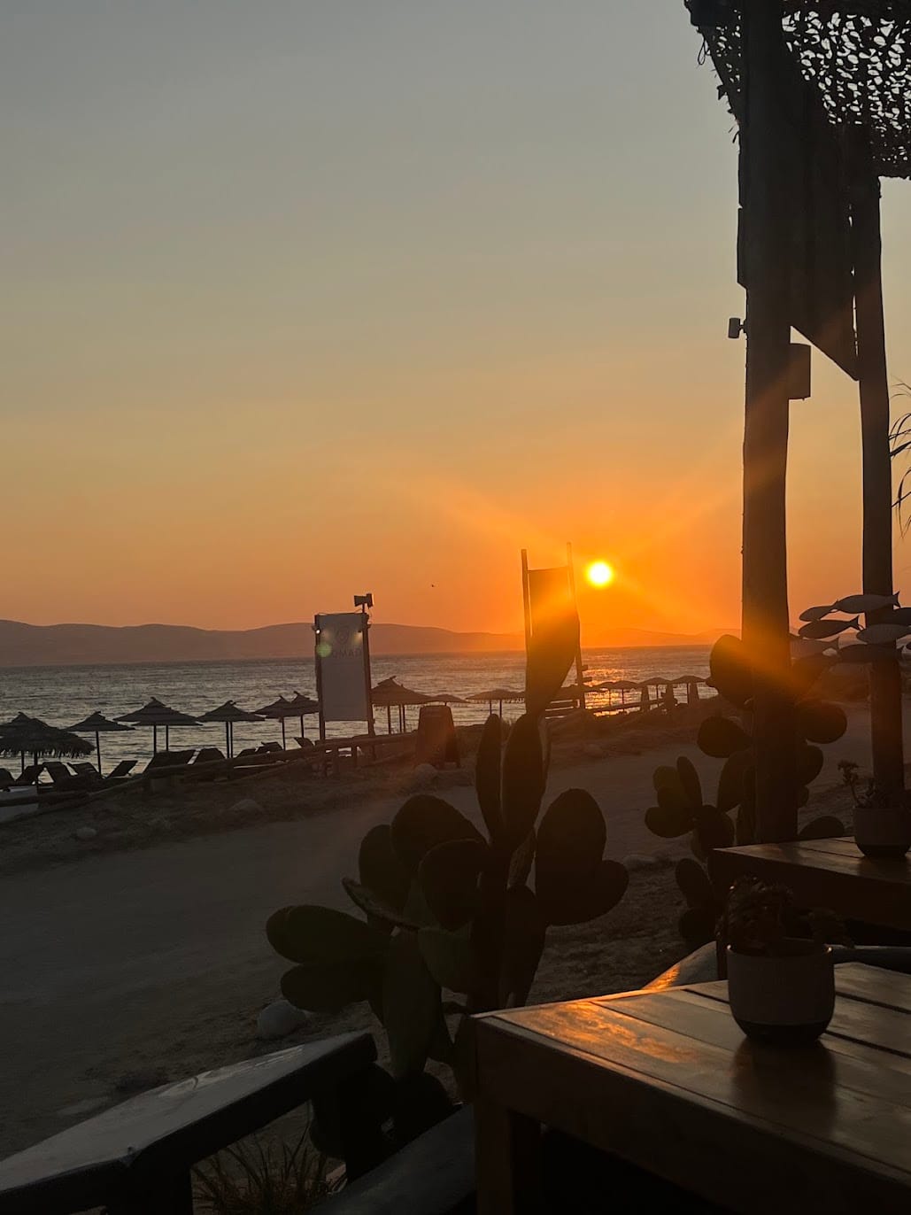 The sun setting over the sea beyond the beach