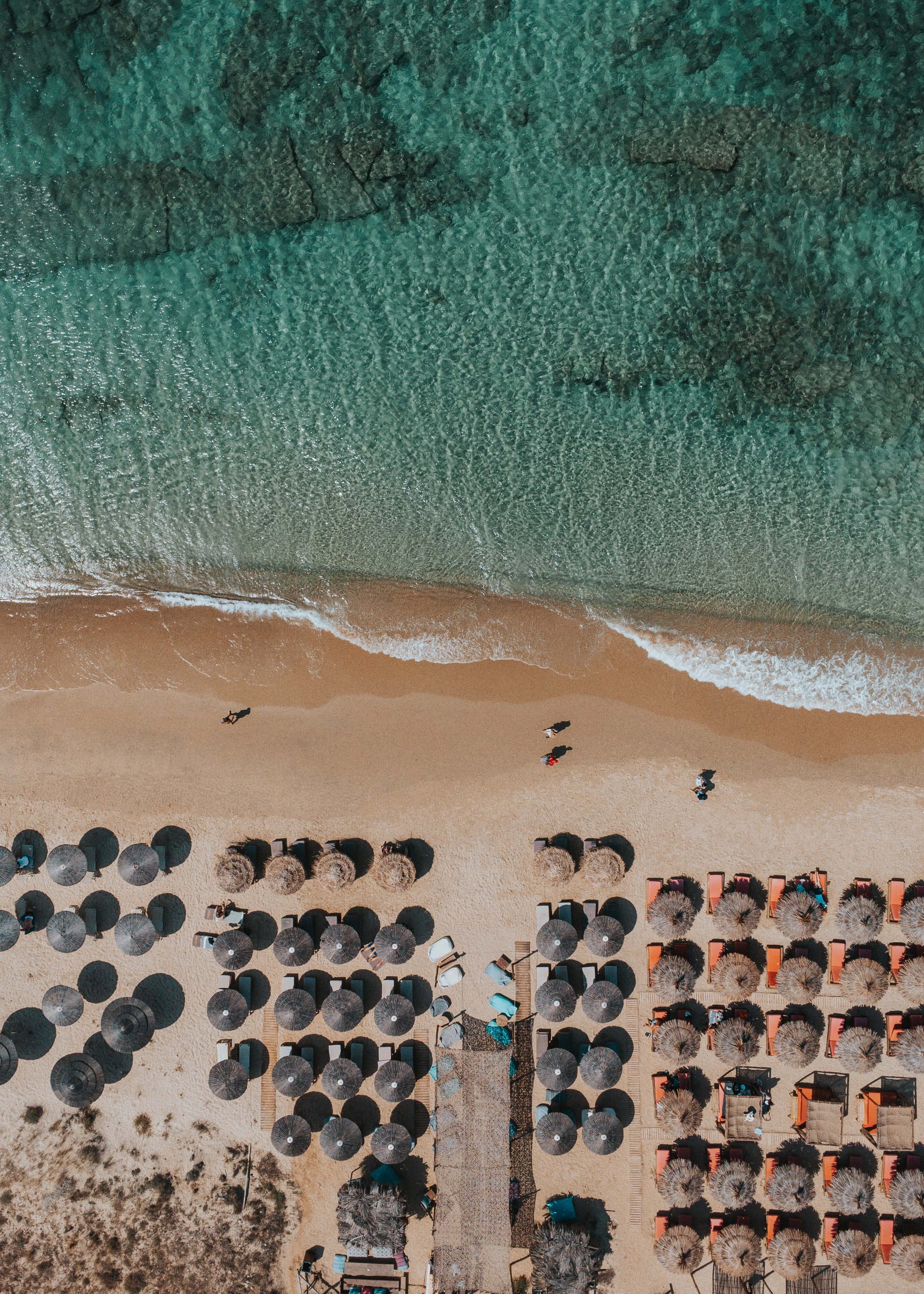 Aerial view of beach umbrellas along the turquoise Aegean shore