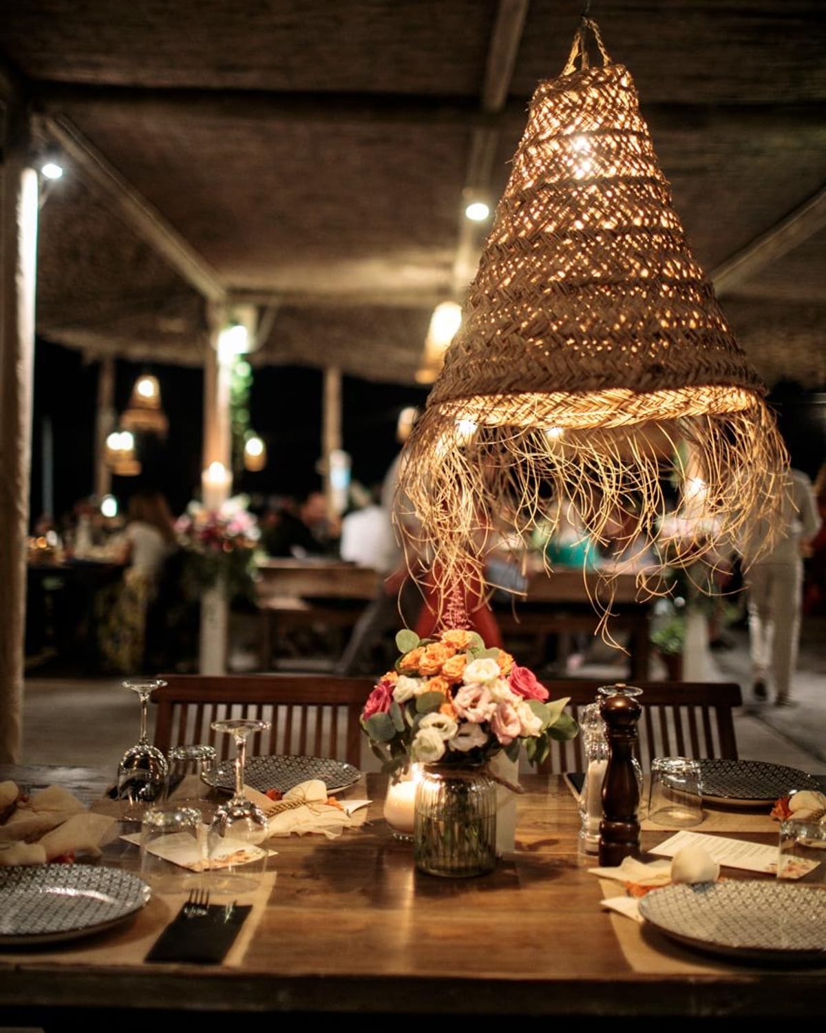 Candle-lit tables under the reed canopy in the evening