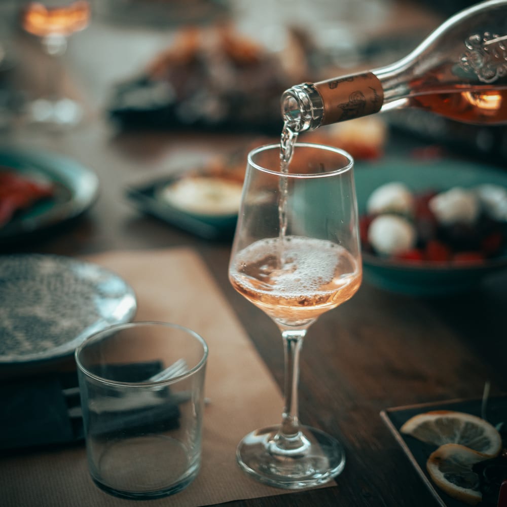Rosé being poured at a candle-lit dinner table
