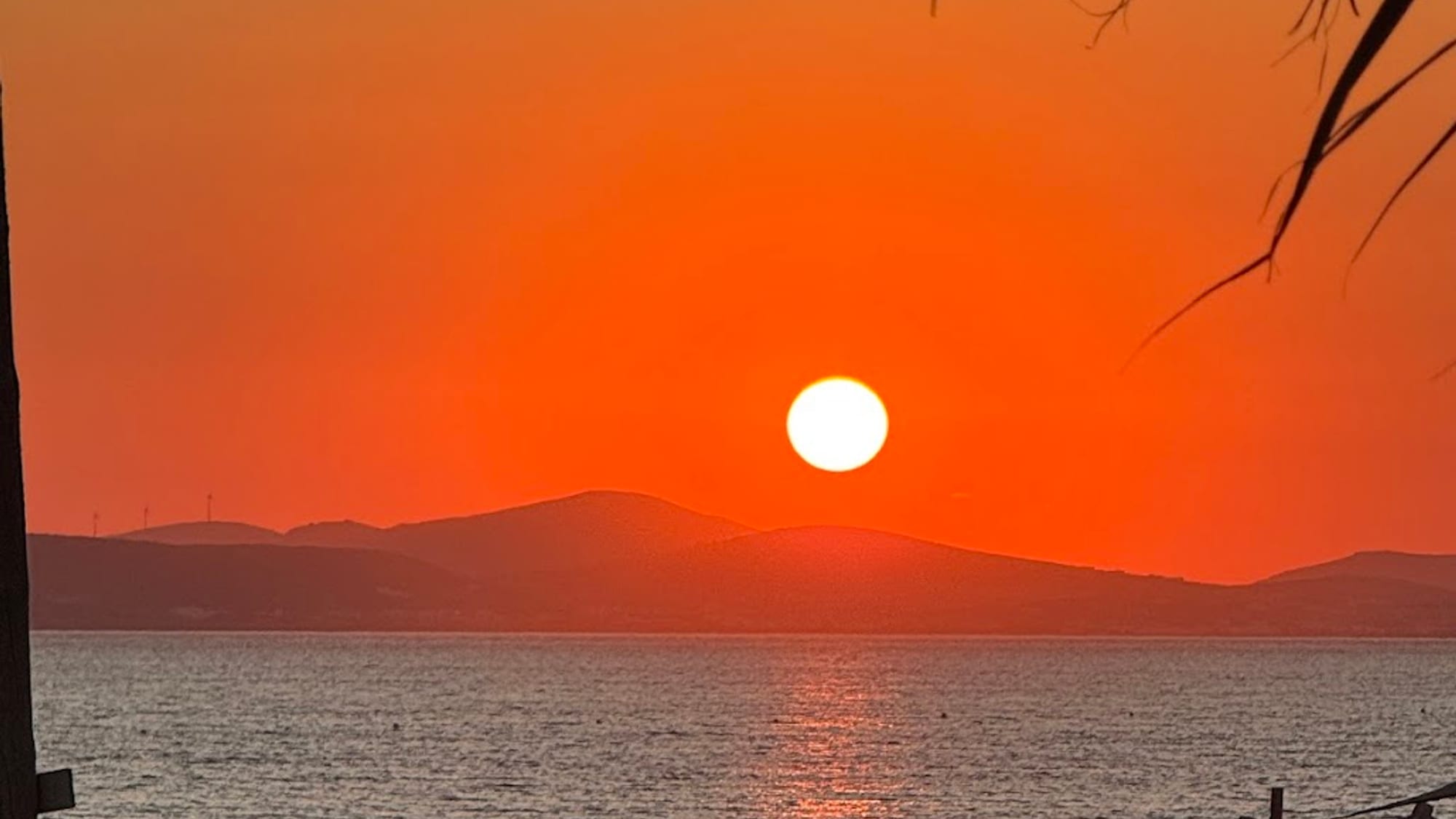 The sun setting over the sea beyond the beach umbrellas