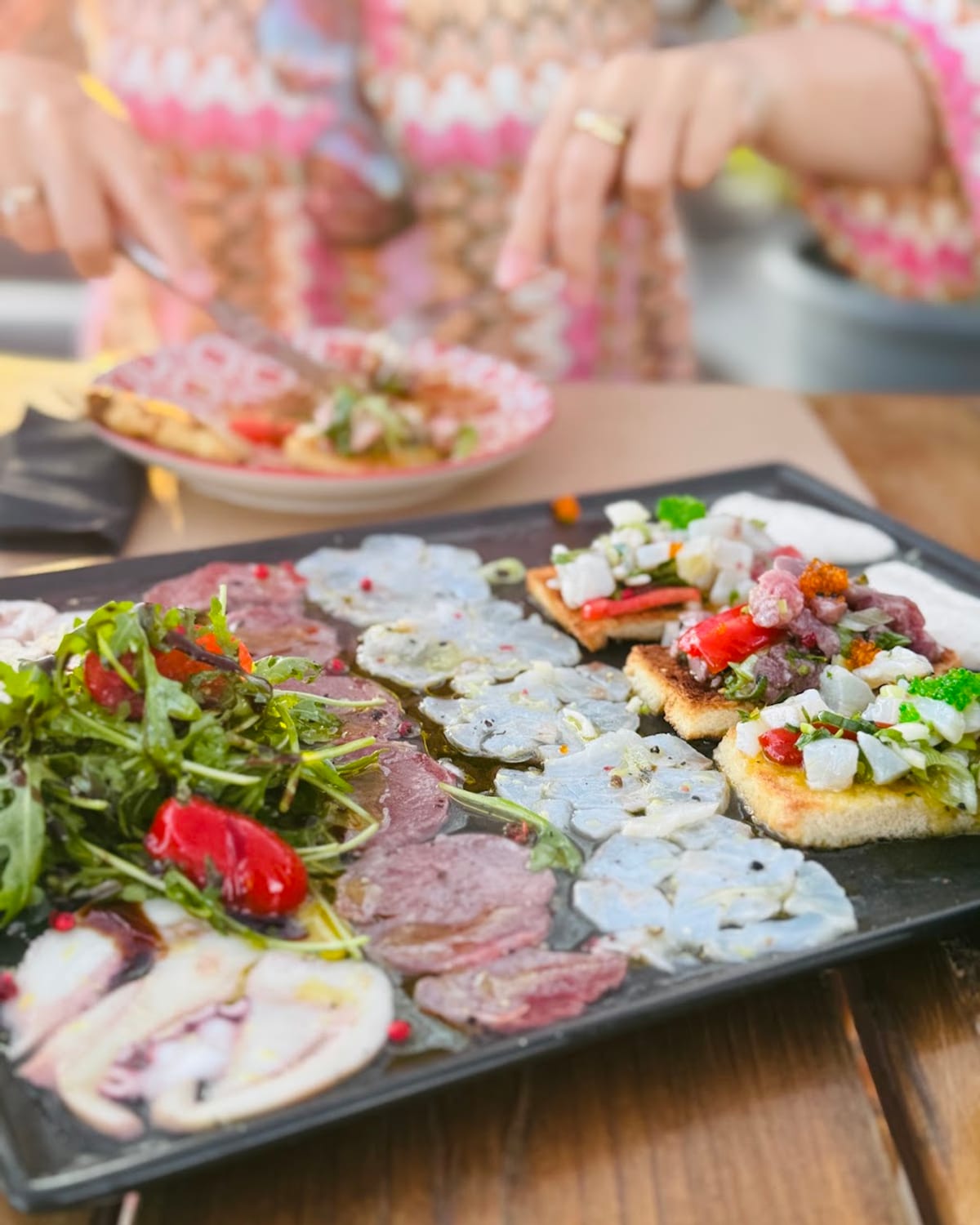 The raw fish plate — carpaccio, ceviche and tartare on a black platter